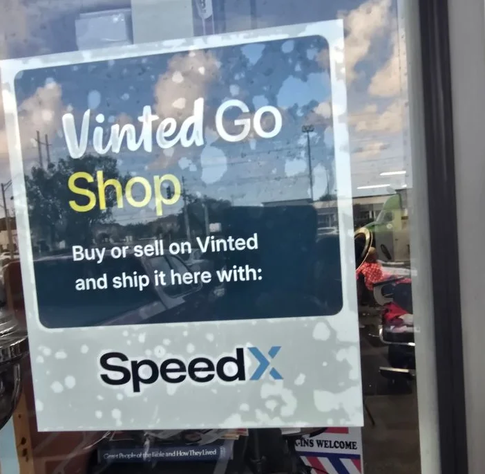 Vinted Go Shop and SpeedX sign on the window at Prestige Barbers Atlantic Blvd